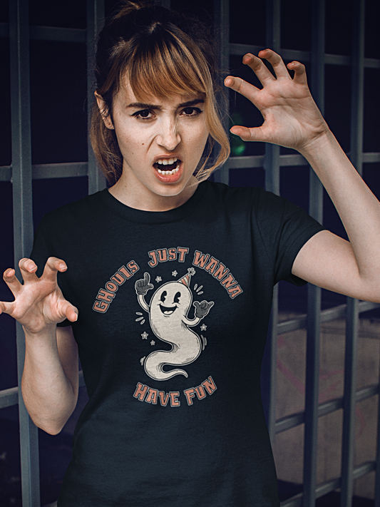 A woman wearing a black graphic t-shirt with a cartoon ghost and the text 'GHOULS JUST WANNA HAVE FUN'. She is posing with clawed hands in front of a dark metal window.