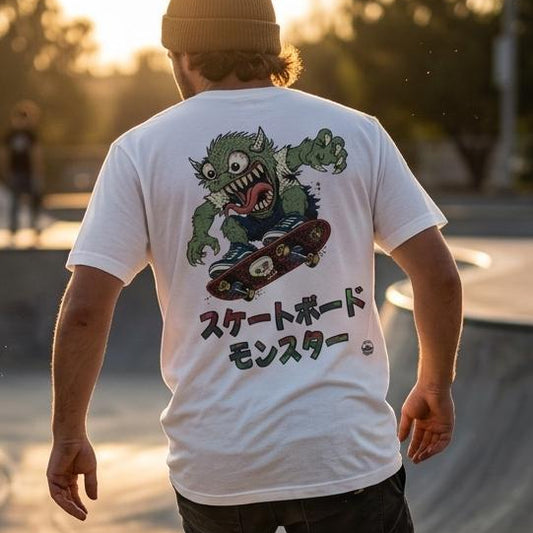 A person skateboarding in a concrete bowl at sunset, viewed from behind. The main visible product is a white graphic T-shirt with a large green monster illustration and Japanese text on the back.